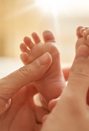 mum-making-baby-massage-mother-massaging-infant-bare-foot-preventive-massage-newborn-mommy-stroking-baby-s-feet-with-both-hands-light-background